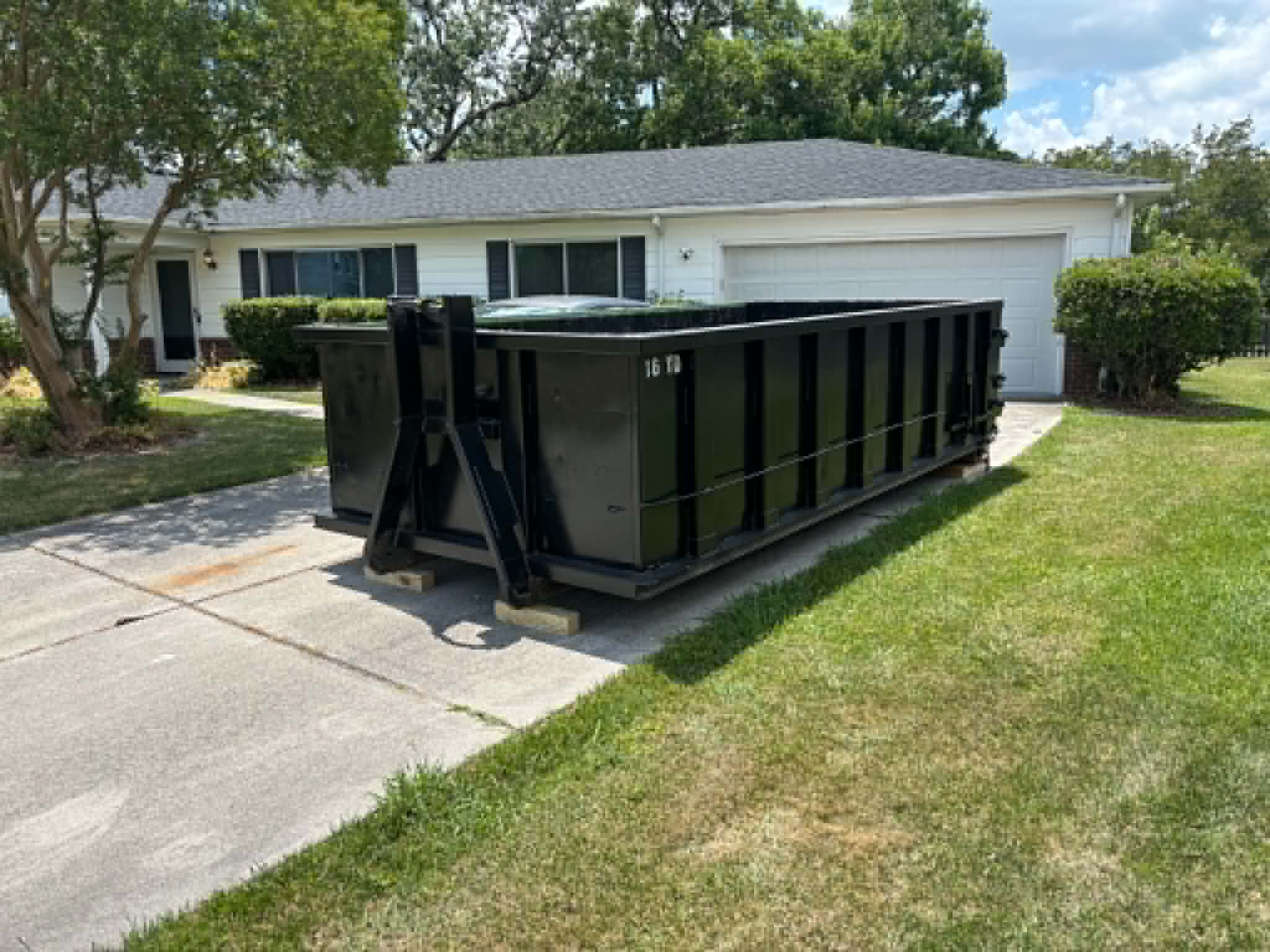 RISE Dumpsters 10-yard container dropped safely on a residential driveway with wood board driveway protection.